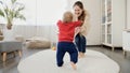 1 year old baby boy learning walking and making steps on carpet towards laughing mother. Baby development, family playing games, Royalty Free Stock Photo