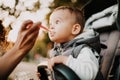 1 year old baby eating yogurt in stroller in city park Royalty Free Stock Photo