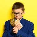 An 11-year-old boy in an adult and oversized suit holds a euro, a portrait of a child with money on a yellow background Royalty Free Stock Photo