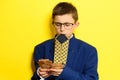 An 11-year-old boy in an adult and oversized suit holds a euro, a portrait of a child with money on a yellow background. Royalty Free Stock Photo