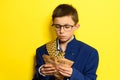 An 11-year-old boy in an adult and oversized suit holds a euro, a portrait of a child with money on a yellow background. Royalty Free Stock Photo