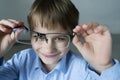 A 9-year-old boy in a blue shirt with glasses checks his eyesight. You should wear glasses. Eye health care