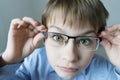 A 9-year-old boy in a blue shirt with glasses checks his eyesight. You should wear glasses. Eye health care