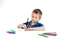 A 6 year old boy in a blue shirt paints with pencils on a white background isolate Royalty Free Stock Photo