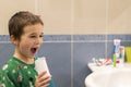 A 5-year-old boy at home washes his teeth with an oral irrigator. Little boy cleaning teeth with oral irrigator. Dental Care