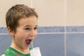 A 5-year-old boy at home washes his teeth with an oral irrigator. Little boy cleaning teeth with oral irrigator. Dental Care