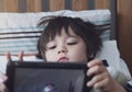 5 year old boy lying In bed playing game on tablet in bedroom in the morning,Little boy watching cartoon on digital tablet,