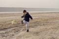 A 4-year-old boy plays soccer on an empty beach Royalty Free Stock Photo