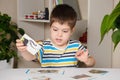 A 4-year-old boy puts together a picture of a raccoon from puzzles while sitting at the table. Royalty Free Stock Photo