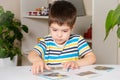 A 4-year-old boy puts together a picture of a raccoon from puzzles while sitting at the table. Royalty Free Stock Photo