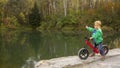 A 5-year-old boy sits on a bicycle by the pond and points to the distance.