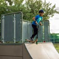 10-year-old boy in sportswear rides a scooter with half pipes. Trains at skatepark. the teenager is wearing a helmet on his head. Royalty Free Stock Photo