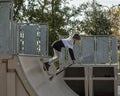 10-year-old boy in sportswear rides a scooter with half pipes. Trains at skatepark. the teenager is wearing a helmet on his head. Royalty Free Stock Photo