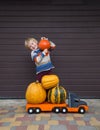 5 year old boy standing with a pumpkin on his shoulder near a toy car truck loaded with large pumpkins Royalty Free Stock Photo