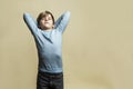 A 9-year-old boy stretches tiredly. A handsome guy in a blue sweater and gray jeans. Difficulties in learning and stress. Yellow Royalty Free Stock Photo