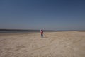 A 10 year old boy in a white sweatshirt and orange vest launches a kite on a deserted beach in solitude