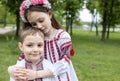 4-year-old boy, 7-year-old girl in national Ukrainian embroidered clothes sit embracing