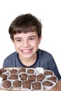 9 year old child holding a tray with several Brazilian fudge balls and with a big smile