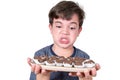 9 year old Brazilian holding a tray with several Brazilian fudge balls and making an angry face