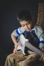 8 year old British Indian boy practices the electric guitar at home.