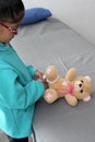 4-year-old brunette Latina girl with glasses represents mistreatment and physical abuse in her teddy bear with bandages on her hea