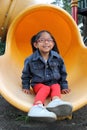 4-year-old brunette Latina girl plays on the slide in the park living in poverty and happy