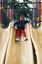 4-year-old brunette Latina girl plays on the slide in the park living in poverty and happy