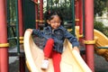 4-year-old brunette Latina girl plays on the slide in the park living in poverty and happy