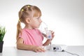 A 5-year-old caucasian girl is breathing into an inhaler at home. Treatment of cough and lung diseases in children, dilution of