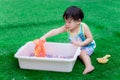 2 year old child boy is playing colorful water beads in white basin.