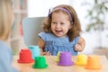 2 year old child playing with educational cup toys at home.