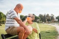 65 year old couple with surgical mask looking at each other on a bench in a park Royalty Free Stock Photo
