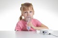 A 5-year-old caucasian girl is breathing into an inhaler at home. Treatment of cough and lung diseases in children, dilution of