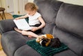 6 year old girl child reading a book out loud to an real animal guinea pigs at home, practicing reading and confidence. Royalty Free Stock Photo