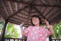 A 5 year old girl dances in a gazebo covered with natural leaves. The young kid showed a cute face.