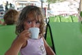 A 4 year old girl drinks a decaf in a Toroni bar in Greece