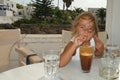 4 year old girl drinks decaffeinated coffee frappe during her holidays in Greece