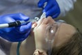 An 11-year-old girl with glasses is treating her front teeth. Portrait of a cute baby in a somatologist chair. Dental fillings