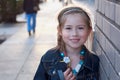 Cute, elementary aged girl smiling at camera on city street