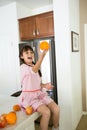 Playful girl in kitchen with oranges Royalty Free Stock Photo