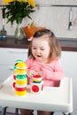 A 2 year old girl with long hair plays with a designer construction at home, builds towers, rejoices at successes, vertical photo