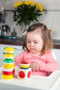 A 2 year old girl with long hair plays with a designer construction at home, builds towers, rejoices at successes, vertical photo Royalty Free Stock Photo