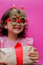 A 3-year-old girl in a red and white dress with a gift in her hands. The gift is packed in kraft paper with a red ribbon Royalty Free Stock Photo