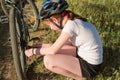 11-year-old girl repairs a bicycle in the countryside. Teenage girl repairing a bike while traveling Royalty Free Stock Photo