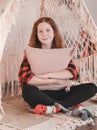 Girl is sitting in a tent indoors. Red-haired girl hugging a pillow