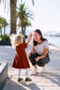 2-year old girl is splashing water from the fountain on her mother on a boat pier Royalty Free Stock Photo