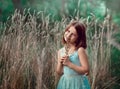 A 10-year-old girl stands near tall dry grass and holds a bouquet in her hands. The girl is holding a bouquet. Royalty Free Stock Photo