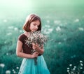 A 10-year-old girl walks in a field with white flowers. The girl is holding a bouquet. Royalty Free Stock Photo