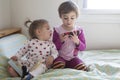 4-year-old girl watching cell phone and 1-year-old girl reading book Royalty Free Stock Photo