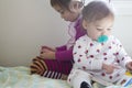 4-year-old girl watching cell phone and 1-year-old girl reading book Royalty Free Stock Photo